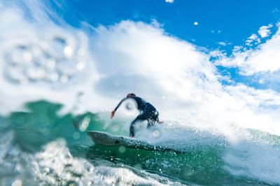 Man surfing in sea against sky