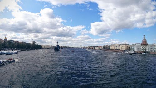 Boats in river against cloudy sky