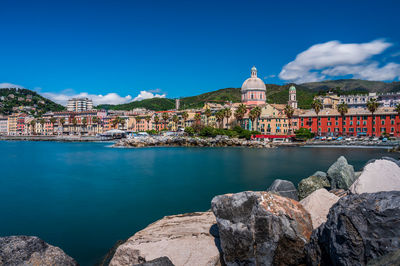 Buildings by sea against sky