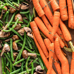 Macro view of oven roasted vegetables including beans, mushrooms and carrots.