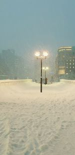 Snow covered street and buildings against sky