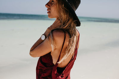 Side view of woman standing at beach against sky