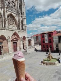 Woman holding ice cream against buildings in city