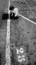 High angle view of girl crouching on road