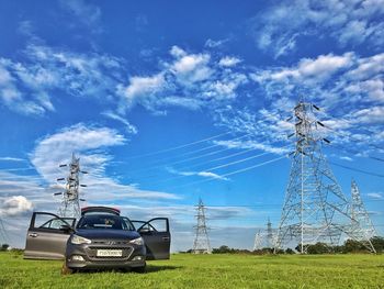 Electricity pylon on field against blue sky