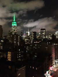 Illuminated cityscape against cloudy sky