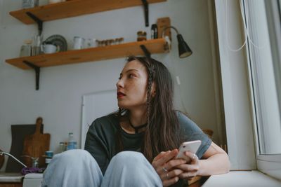 Sad woman with smartphone at home
