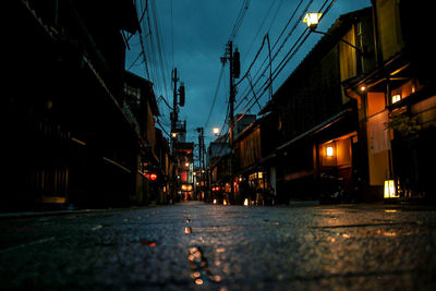 Illuminated street amidst buildings in city at night