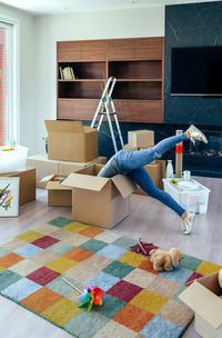 Low section of woman in cardboard box at home