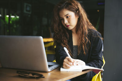 Young woman using phone while sitting on table