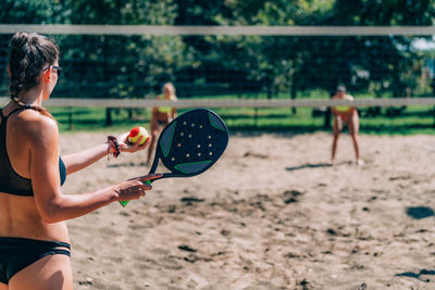 Female friends playing beach tennis