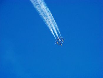 Low angle view of airshow against clear blue sky