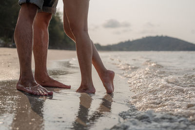 Low section of couple standing on beach