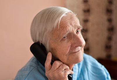 Close-up of a 90-year-old elderly retired woman who is talking smiling on the phone. selective focus