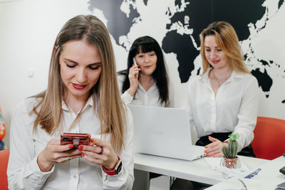 Travel agency working on-line in office, communicating with clients via phone  over the world map. 