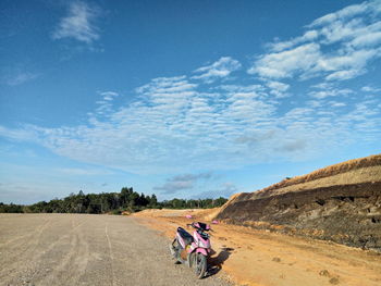 People riding motorcycle on landscape against sky