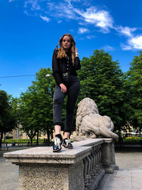 Full length of smiling woman sitting against sky