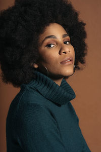 Portrait of young woman standing against gray background