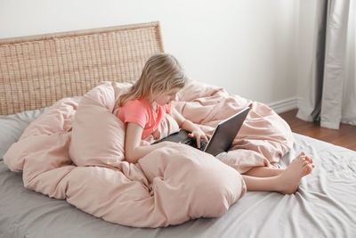 Girl sitting in bed and learning in virtual online school class. kid homeschooling 