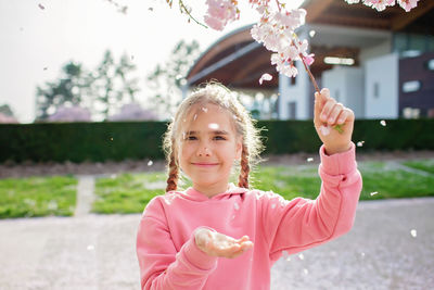 A girl enjoys sakura blossoms while walking through the cherry orchard in spring