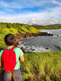 Rear view of boy walking on field against sky