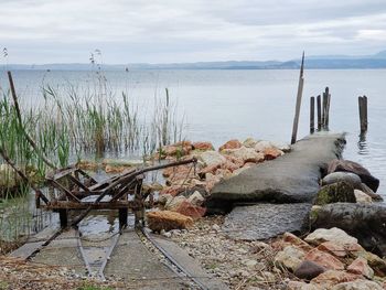 Wooden posts in sea against sky