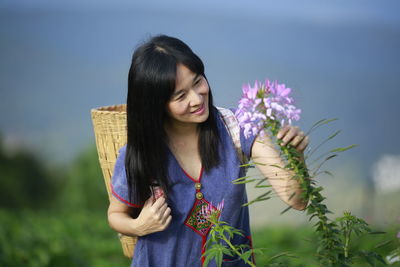 Beautiful woman standing by purple flowering plant