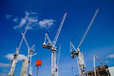 Low angle view of cranes against blue sky