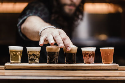 Midsection of mid adult man arranging beer glass on table