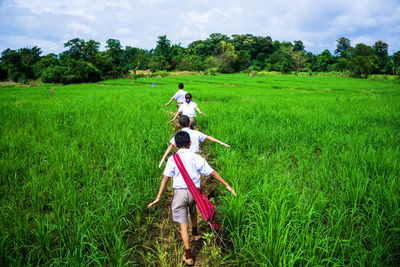 Rear view of women on field against sky