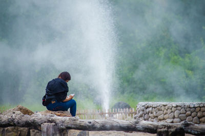 Woman sitting against fountain