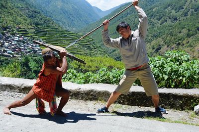 Full length of friends fighting against mountain