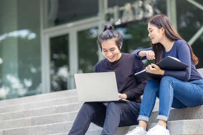 Young woman using mobile phone while sitting outdoors