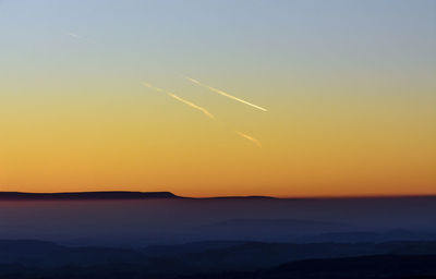 Scenic view of vapor trails in sky during sunset