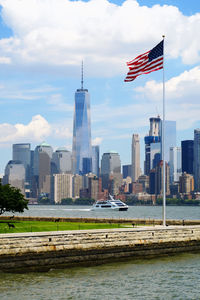 Modern buildings by river against sky in city