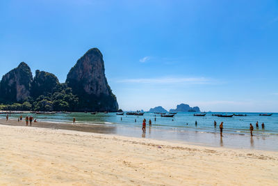 People at beach against mountain