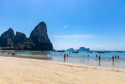 People on beach against blue sky