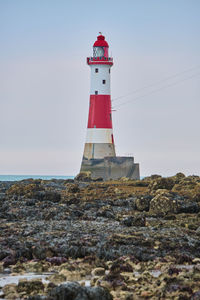 Lighthouse by sea against sky