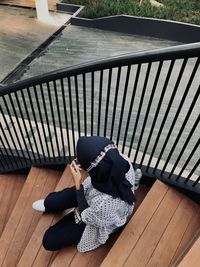 High angle view of woman resting on wooden railing