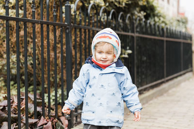 Cute girl wearing warm clothing while standing on sidewalk