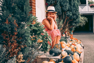 Full length of smiling girl looking away while standing by plants