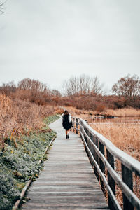 Rear view of person walking on footbridge