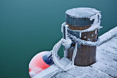 High angle view of frosted bollard and buoy by lake