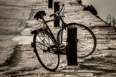 High angle view of bicycle by wooden post on sidewalk