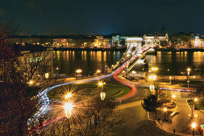 Illuminated city by river against sky at night