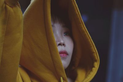 Close-up of young woman in yellow hooded shirt