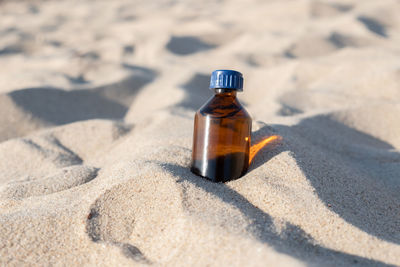 Close-up of bottle on sand at beach