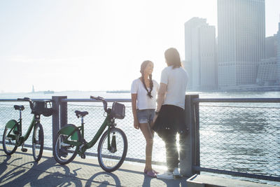 Couple standing by bicycles during sunny day