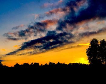 Silhouette of trees against cloudy sky