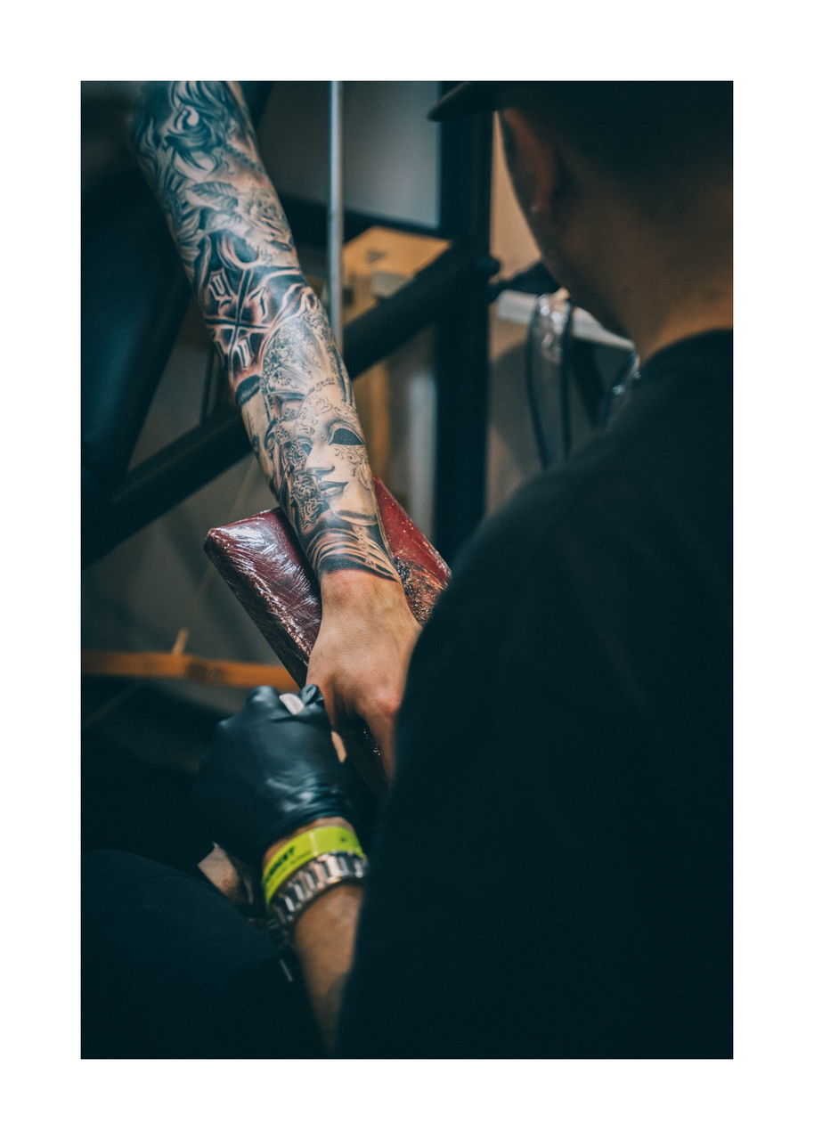 tattoo, real people, indoors, men, lifestyles, adult, two people, creativity, people, human body part, males, women, transfer print, selective focus, human hand, art and craft, body part, fashion, pattern, human leg, human limb, tattooing